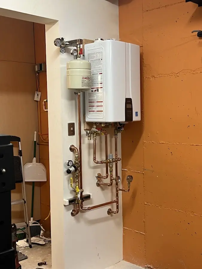 Plumbing technician inspecting water heater connections in Hayden